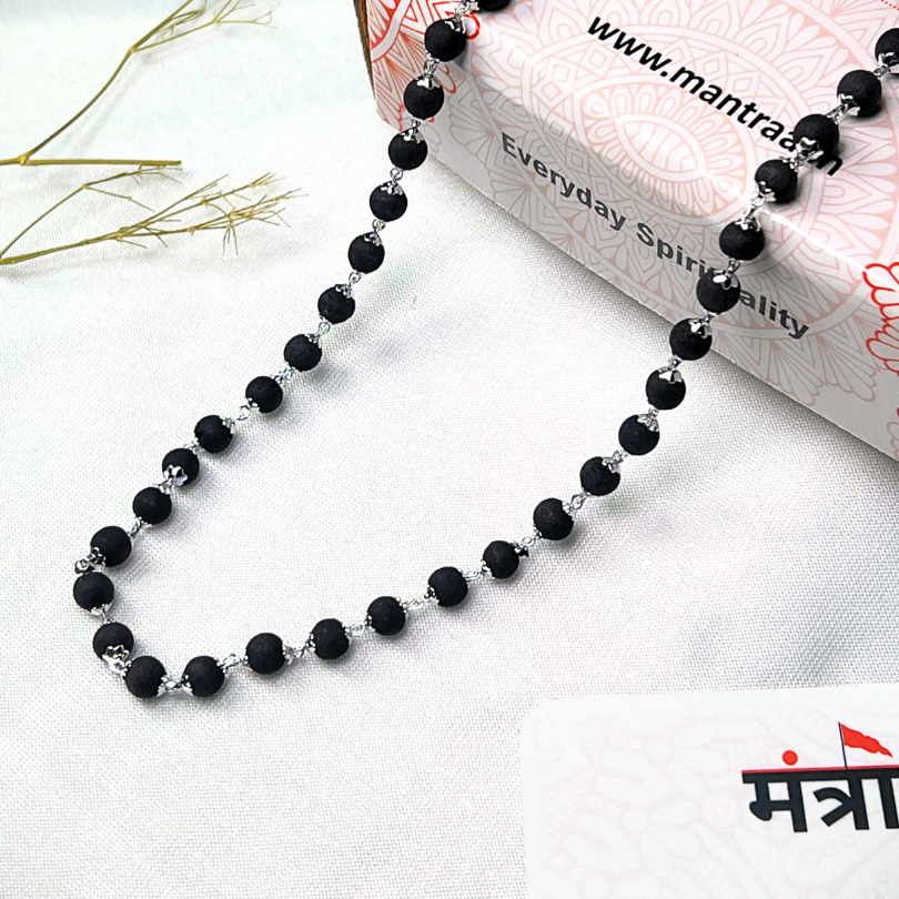 Black beaded necklace on a white surface with a box labeled 'Everyday Spirituality' in the background.