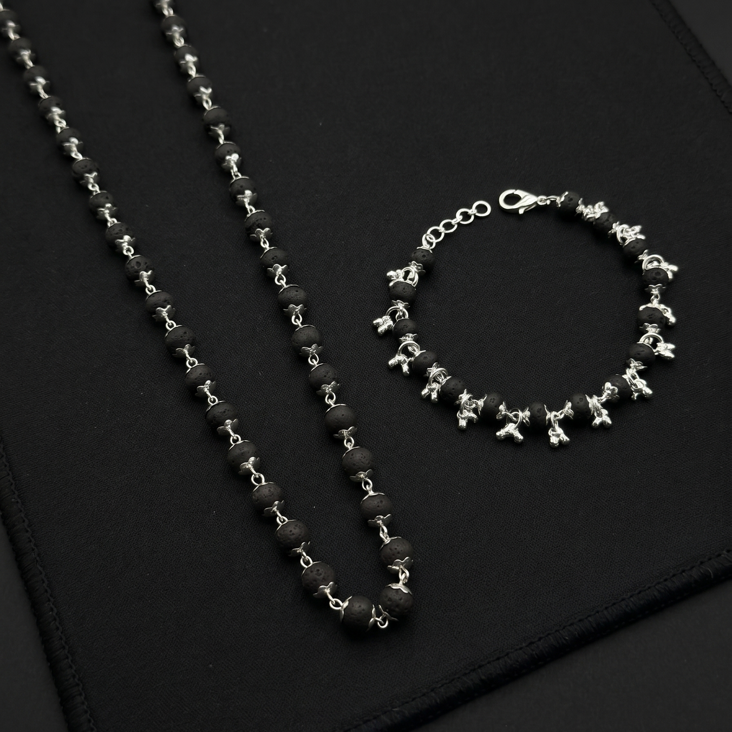 Karungali Silver Plated necklace and bracelet on a black textured surface