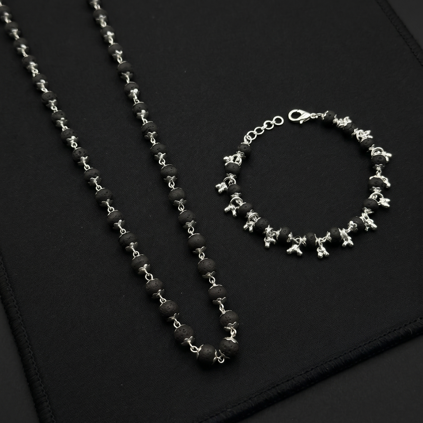 Karungali Silver Plated necklace and bracelet on a black textured surface