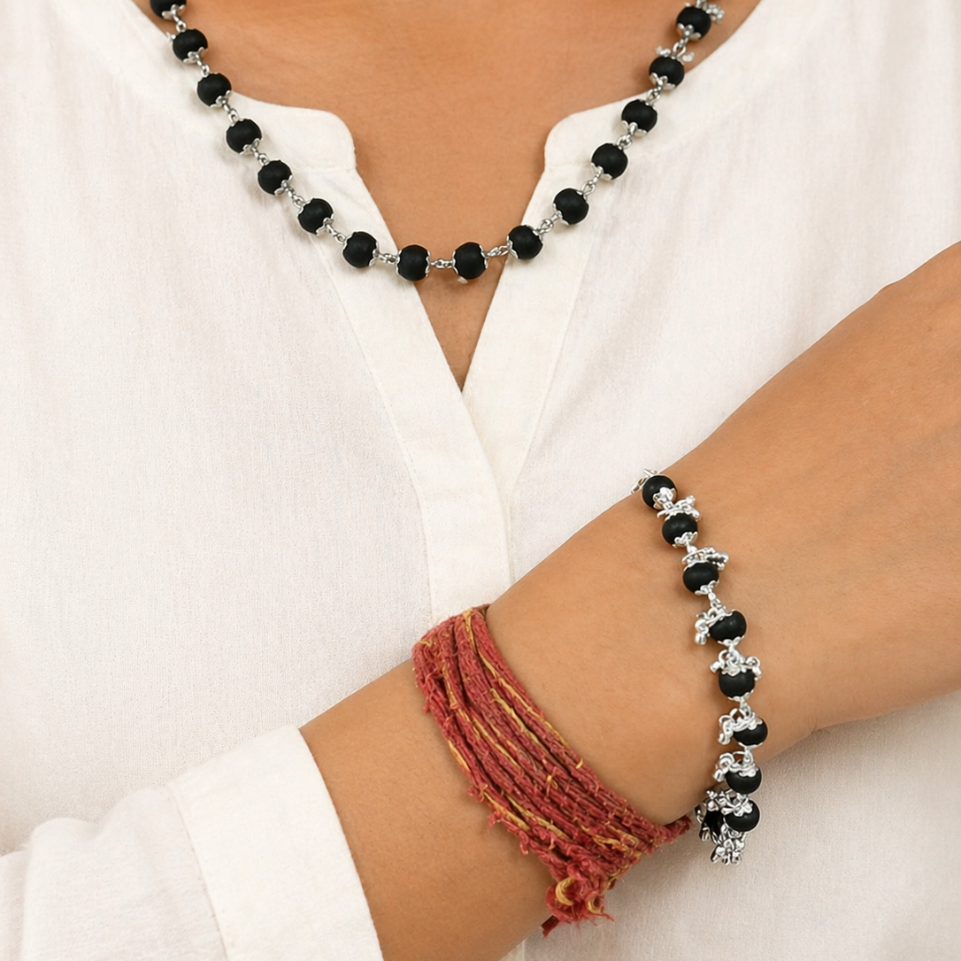 Person wearing a Karungali beaded necklace and bracelet on a white outfit