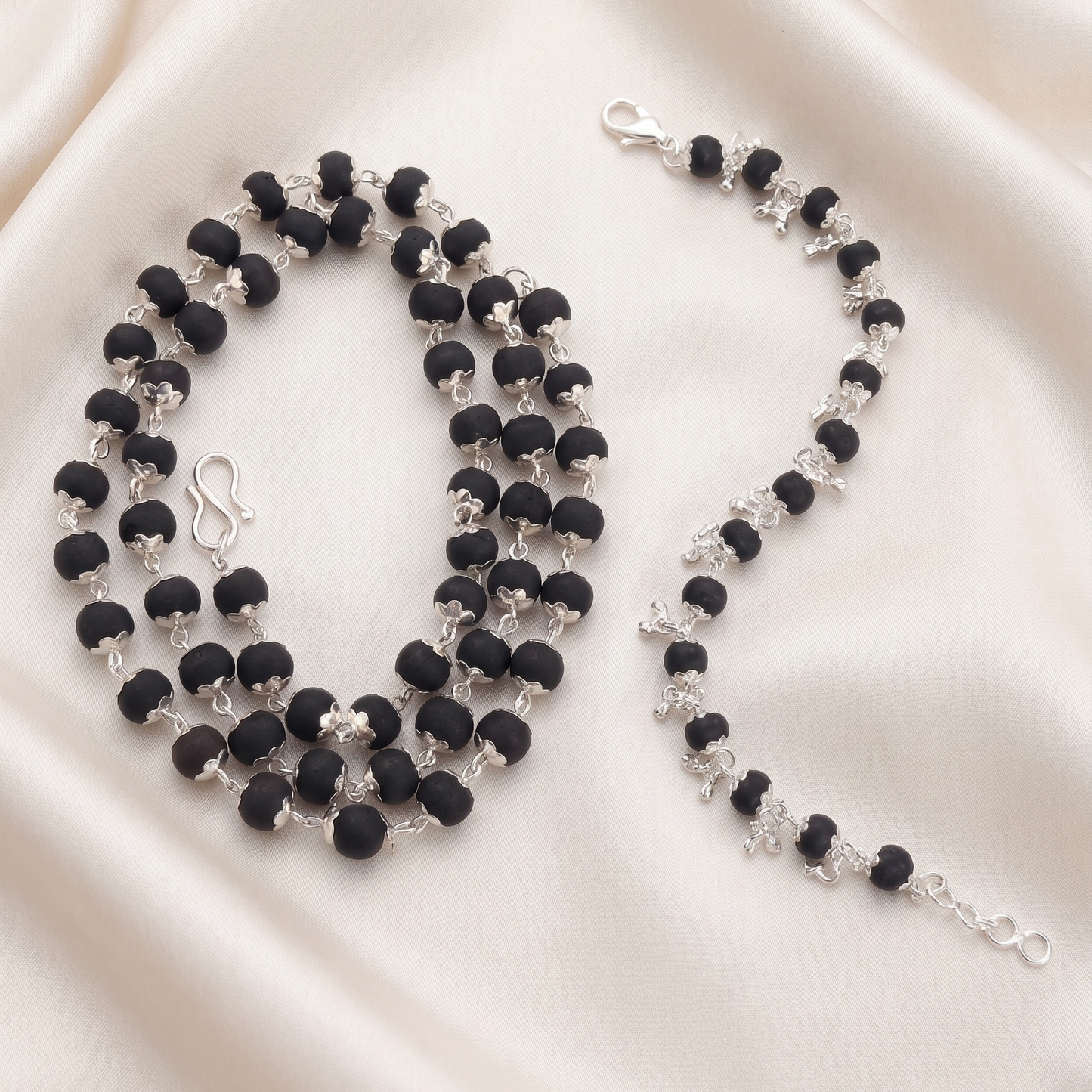 Karungali silver plated beaded necklace and bracelet on a beige satin background