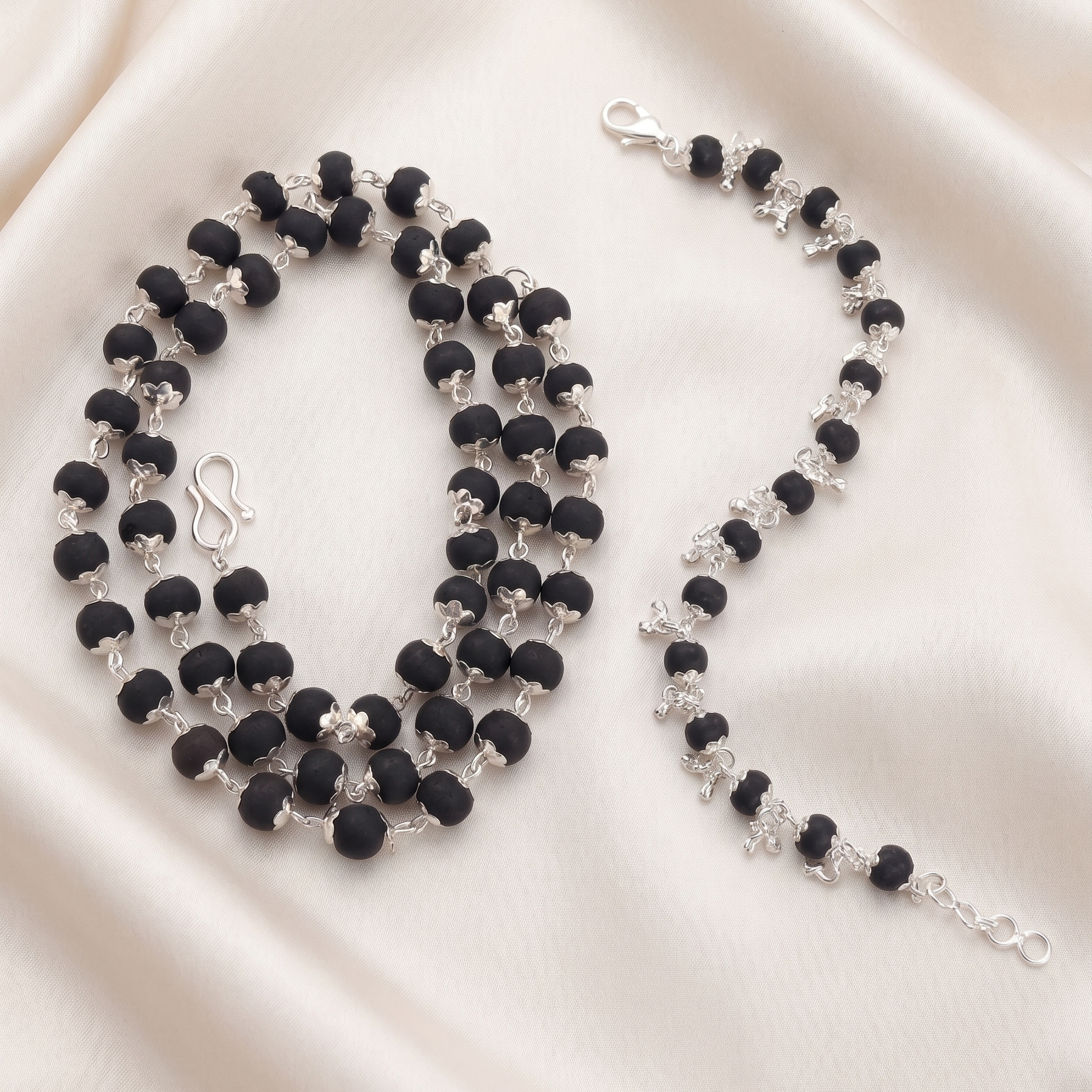 Karungali silver plated beaded necklace and bracelet on a beige satin background