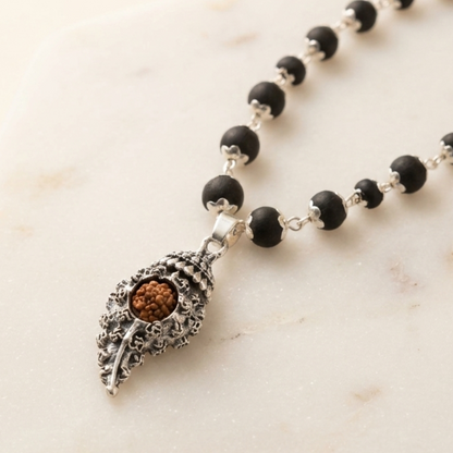 Necklace with black beads and a decorative Shankh Pendant Rudraksha Karungali Necklace on a marble surface