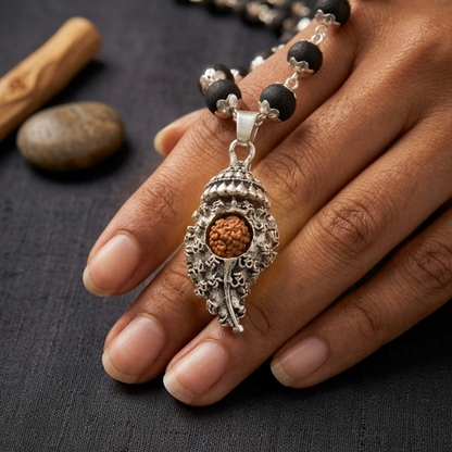 Decorative Shankh Pendant Rudraksha Karungali Necklace with pendant on a hand against a dark background