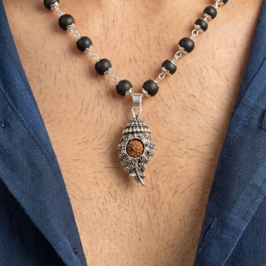 Shankh Pendant Rudraksha Karungali Necklace with black beads and a silver pendant on a person wearing a blue shirt.