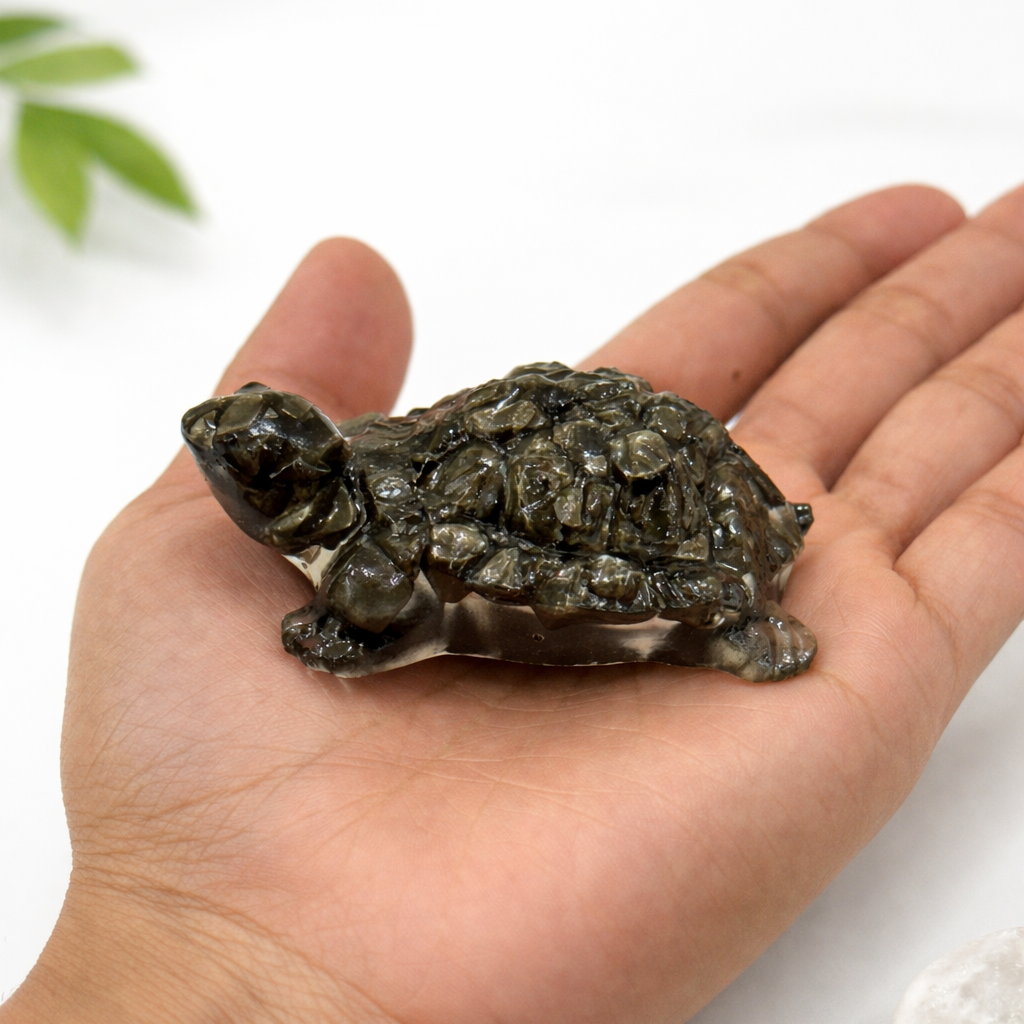 Hand holding a turtle-shaped stone with a white background